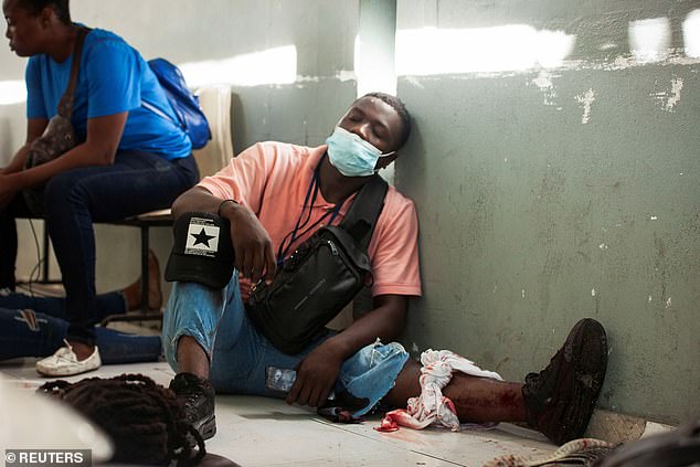 An injured person sits on the ground after armed men opened fire