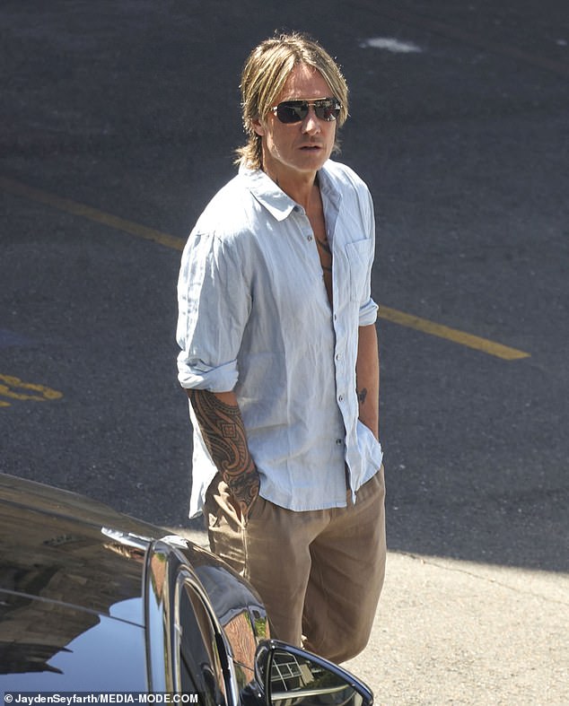 Keith showed off his tattooed arms as he sunbathed while waiting by his vehicle.