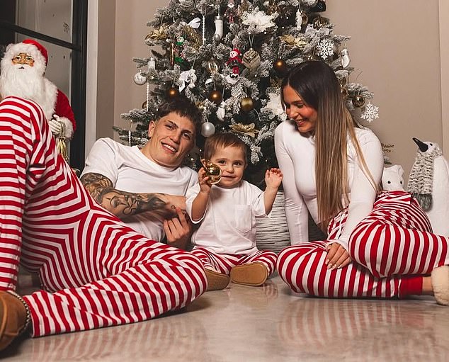 Alejandro Garnacho huddled in front of the tree with his girlfriend Eva García and their young son.