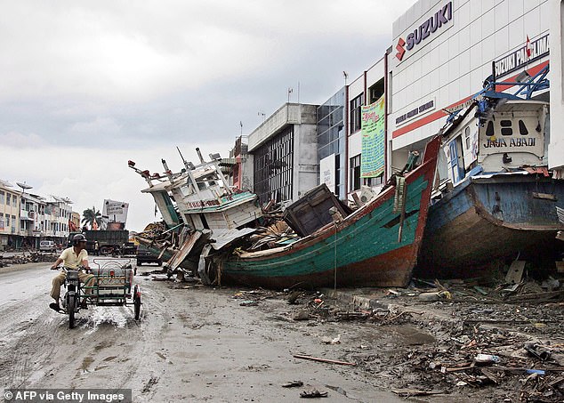 A motorist watches boats that were swept onto a street during the 2004 tsunami in Banda Aceh.