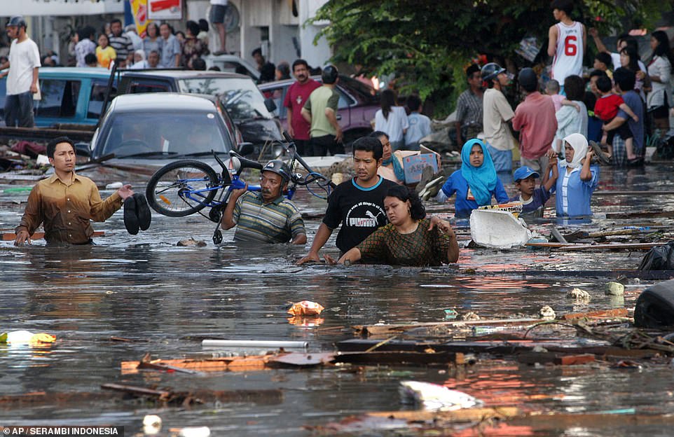 Aceh residents seen wading through flooded street to higher ground shortly after tsunami attack in provincial capital Banda Aceh, Indonesia