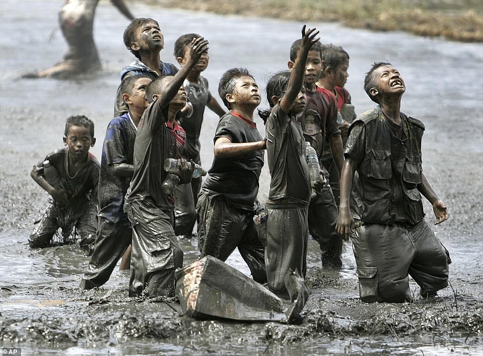 Refugee children try to catch aid dropped from an Australian military helicopter into a rice field in Lampaya, on the outskirts of Banda Aceh, Indonesia, January 17, 2005