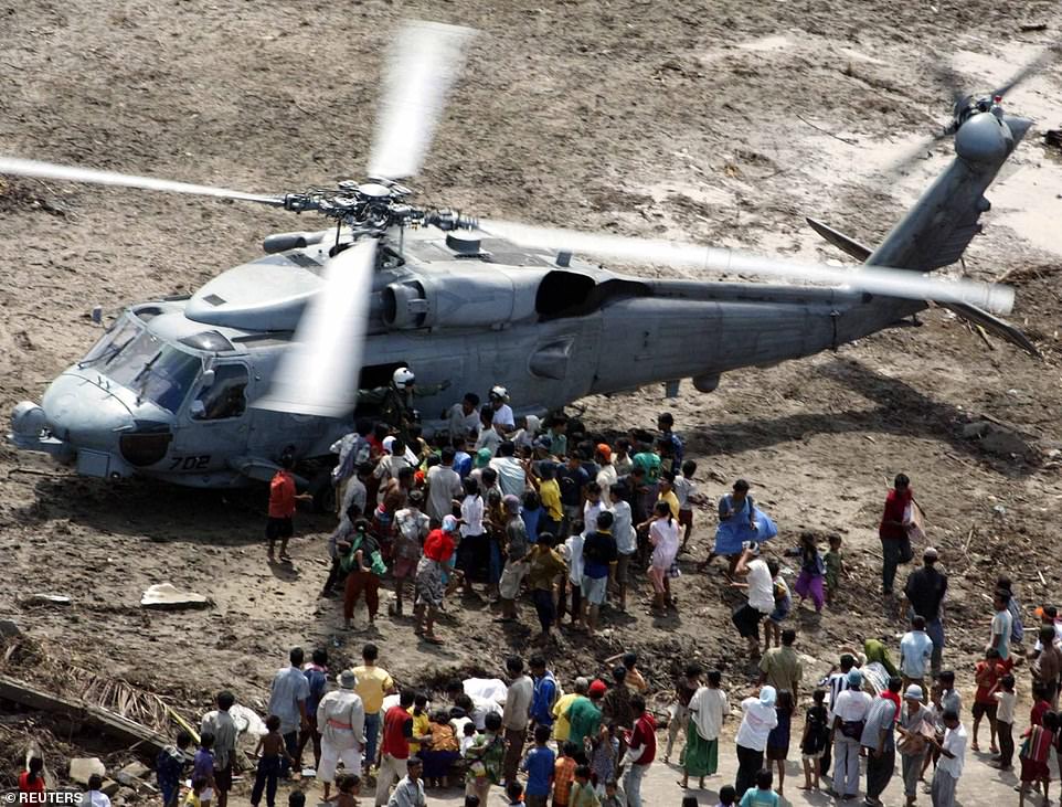 Tsunami refugees receive supplies distributed by the USS Abraham Lincoln Carrier Strike Group in Kouati Sounam, about 90 kilometers south of Banda Aceh, on January 3, 2005.