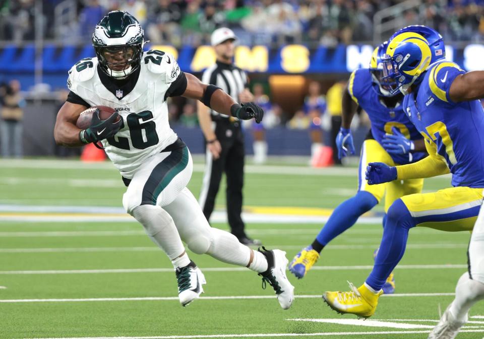 Saquon Barkley, left, runs the ball past Rams safety Quentin Lake