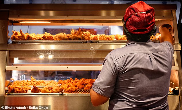 A fast food worker in a chicken shop (file image). Researchers at University College London have warned that highly processed foods, which often contain excessive amounts of salt and sugar, are often cheaper than fruits and vegetables.