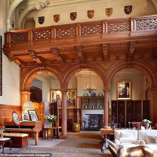 The impressive drawing room, located at the entrance of this 19th-century house, spans two floors and is complete with a wooden dining table, detailed tapestries, cream sofas and a piano, topped with photographs.