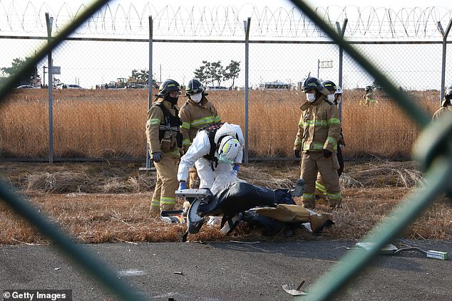 Members of the South Korean rescue team search near the wreckage of the plane