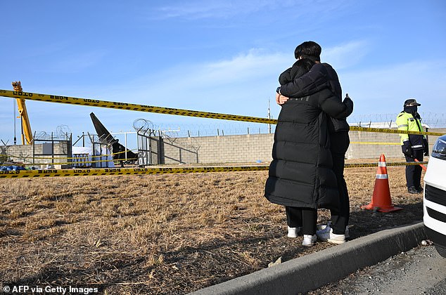 Mourners react near the scene where a Jeju Air Boeing 737-800 series plane crashed and caught fire at Muan International Airport