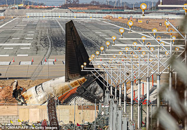 The destroyed tail section of the Jeju Air Boeing 737-800 aircraft that crashed and caught fire is seen at the end of the runway at Muan International Airport