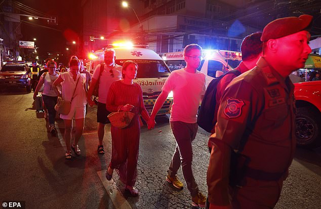 A police officer escorts tourists who were evacuated from the hotel