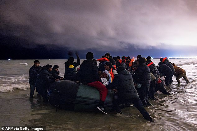 Migrants board a smugglers' inflatable boat in an attempt to cross the English Channel, at Bleriot beach in Sangatte, near Calais, northern France, on October 30, 2024.