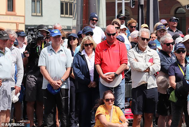 Two wreaths were laid at Constitution Dock, where Mr. Smith and Mr. Quaden would have set foot after finishing the race (people pictured gathering to honor Mr. Smith and Mr. Quaden)