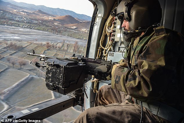 Taliban security personnel stand watch from helicopter two days after Pakistan airstrikes