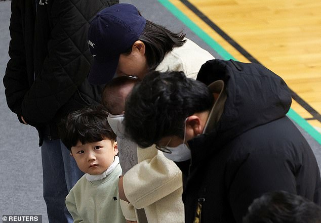 A child watches as mourners visit a memorial altar for the victims of the Jeju plane crash