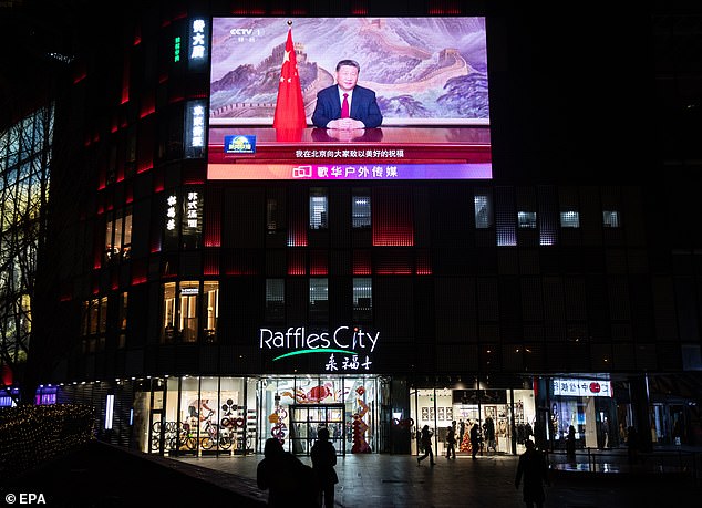 People walk past a screen showing Chinese President Xi Jinping delivering a New Year message in Beijing, China, December 31, 2024.