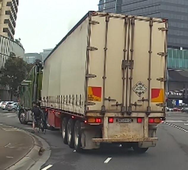 The clip shows the cyclist stopping at the crosswalk to give way to the semi-trailer (pictured left) as the truck enters the merge lane to proceed onto the freeway.