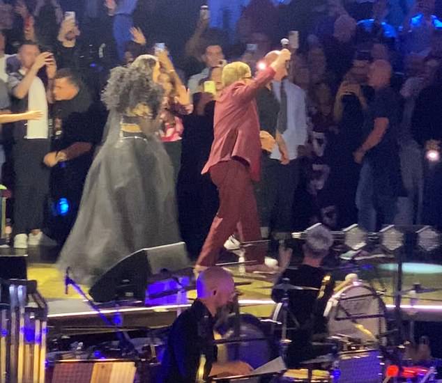 A production assistant extends a supportive hand to the 77-year-old singer as he heads backstage at the Royal Albert Hall on October 17.