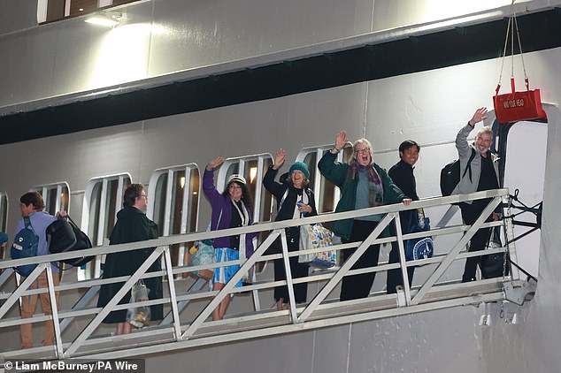 Passengers wave as they board the Villa Vie Odyssey at the Belfast cruise terminal on September 30.