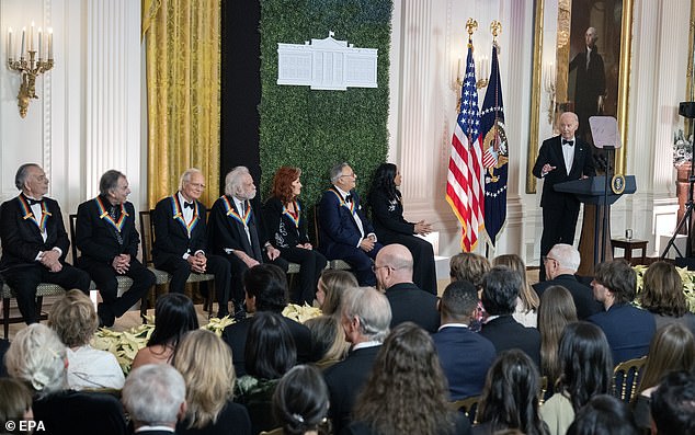 President Joe Biden (right) delivers remarks during a reception for the 47th annual Kennedy Center Honorees in the East Room of the White House. Seated from left to right: filmmaker Francis Ford Coppola; Mickey Hart, Bill Kreutzmann, Bobby Weir of the Grateful Dead; blues rock singer-songwriter Bonnie Raitt; jazz trumpeter Arturo Sandoval; and Michelle Ebanks, president and CEO of the Apollo, which received a special distinction as an Iconic American Institution