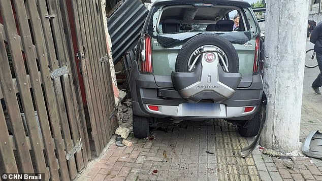 João Barbosa's vehicle became trapped between a light pole and the door of a residence in Praia Grande, Brazil, on Sunday after jumping the curb after rear-ending a bicycle theft suspect and crashing into a mother and her daughter who were riding their own bicycles. the sidewalk