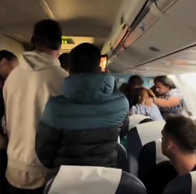 Passengers could be seen trying to push the woman back into her seat after she went on a dramatic tirade.