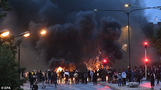 Smoke rises from burning tires, pallets and fireworks during police rioting with a few hundred protesters in the Rosengard neighborhood of Malmo, Sweden, August 28, 2020.