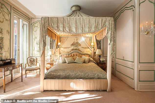 The master bedroom has a private terrace accessed through three sets of charming French doors. The luxurious home has five bedrooms, one of which has an ornate four-poster bed.