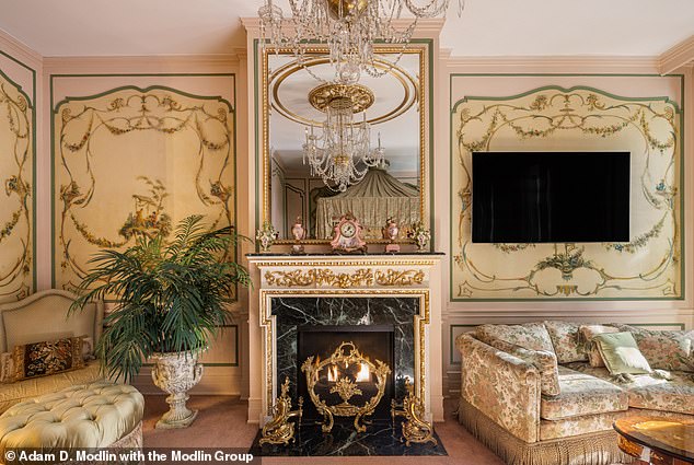 A stunning gold-plated marble fireplace adds a touch of glamor to this majestic living room.