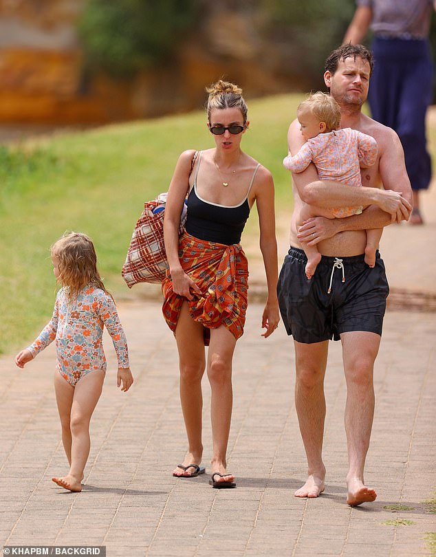 The veteran journalist, 41, flaunted his toned physique in a black swimsuit as he strolled barefoot along the sandy paths.