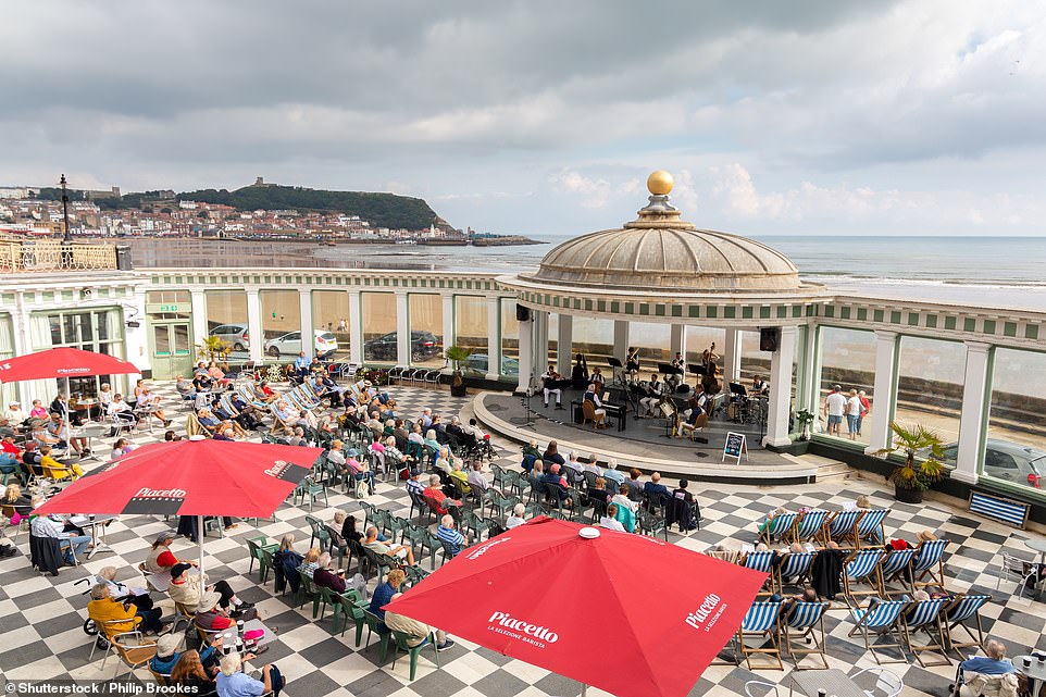 These two images show tourists listening to bands playing at the Spa (a spa and events venue), but more than 100 years apart: the top image dates from 1913 and the bottom image from 2022.