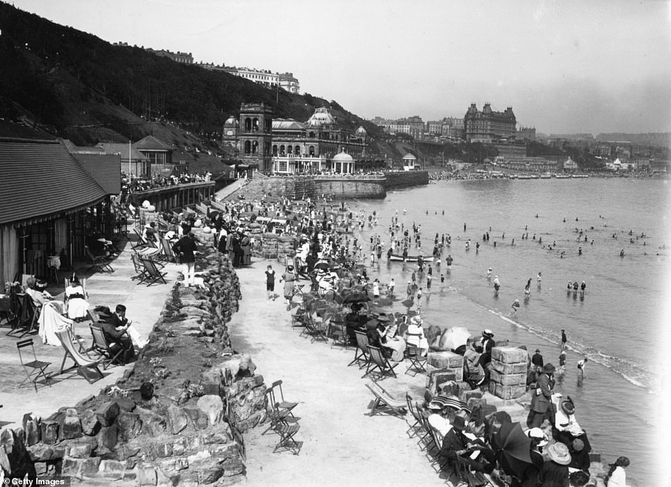 Bathers relax on deck chairs on the shores of Scarborough in 1913. The Spa appears above the beach with the town's Grand Hotel at the top of the image.