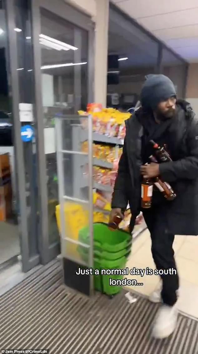 Another thief is seen taking several bottles during the raid on the Asda Express at the Texaco garage on Wandsworth Road, Battersea, south London.