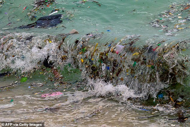 A wave carrying plastic waste and other waste reaches a beach in Koh Samui