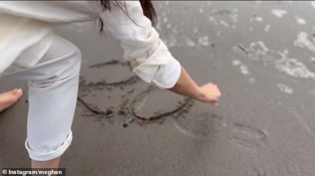 In the clip the former royal is seen working barefoot into the tide of a sandy California beach before writing a near-perfect cursive 2025 in the sand.