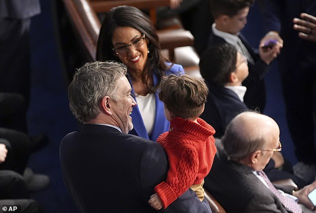 Rep. Thomas Massie, R-Ky., left, holds Rep.'s grandson. Lauren Boebert, R-Colo., as Boebert looks on