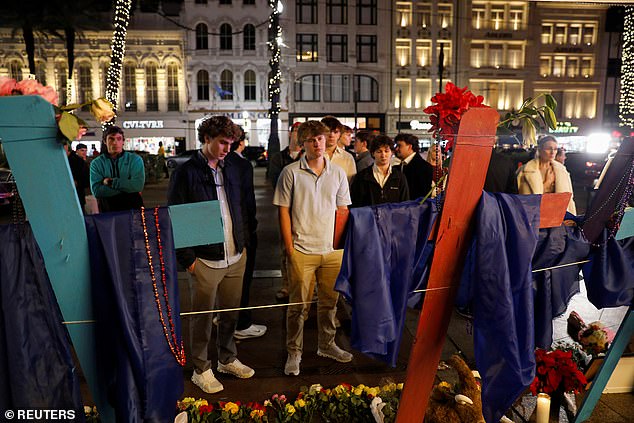 A group of friends mourn the loss of Hubert Gauthreaux, whose photograph is placed on a wooden cross, among others who lost their lives.