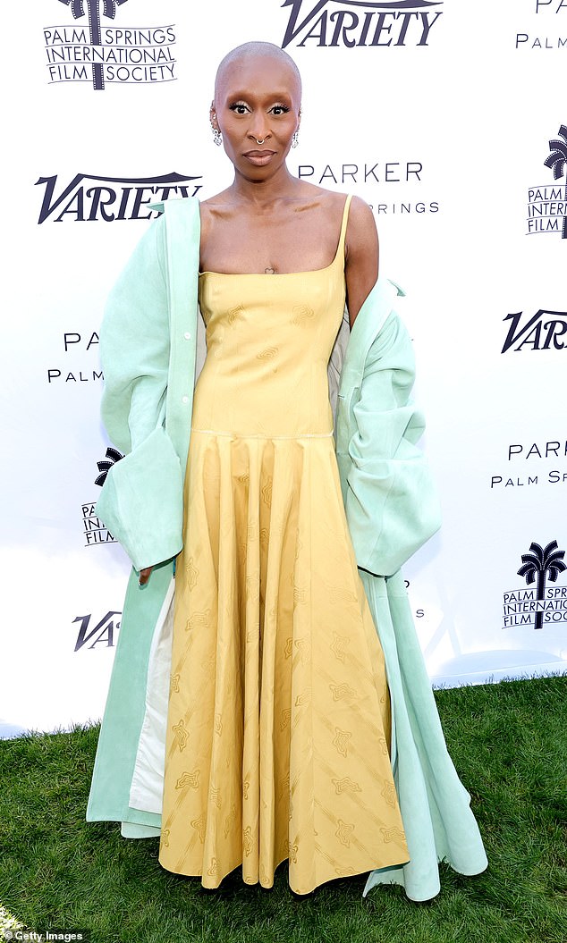 Cynthia Erivo, 37, stood out from the crowd in a long dark lemon dress with a fitted bodice and wide skirt in cotton jacquard and a linden green coat.