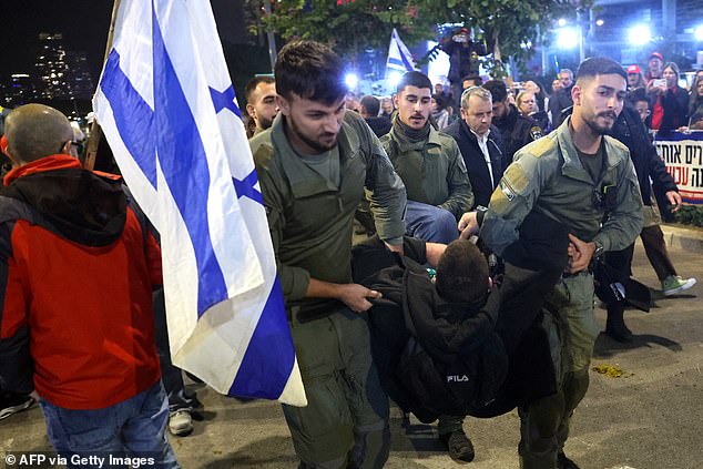 Another protester, this time a man, is led away from the protest by soldiers.