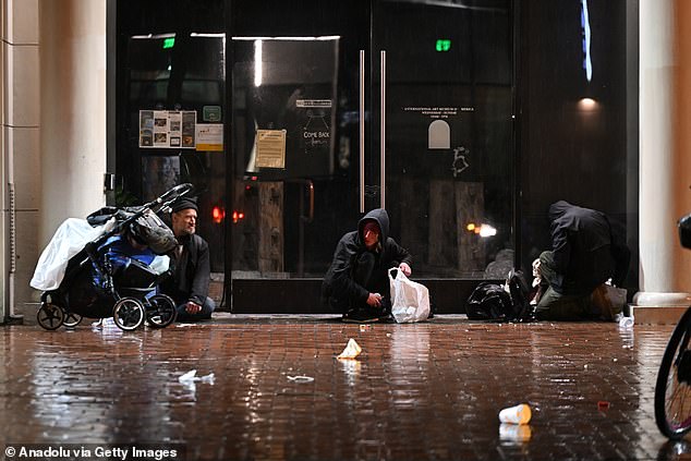 Homeless people are seen near City Hall during heavy rain in San Francisco, California.