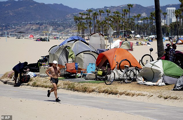 A jogger runs past a homeless encampment in the Venice Beach section of Los Angeles that has begun to make progress against the scourge.