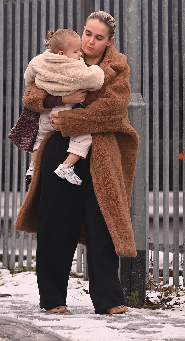 She looked comfortable while out and about in a beige teddy coat which she wore with a black tracksuit and trainers in the snow in Manchester.