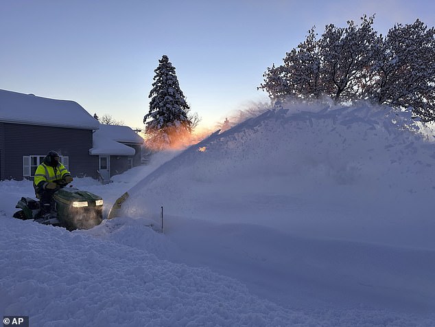 Pictured: A snow plow clears snow as the sun rises in Lowville, New York