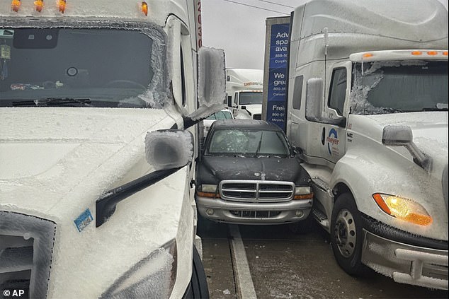 Pictured: A car is stuck between two trucks during frigid weather in Kansas on Saturday