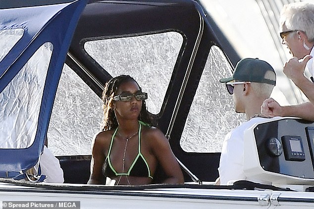 The teens were seen sitting under the shaded area of ​​the boat in green and black bikinis.