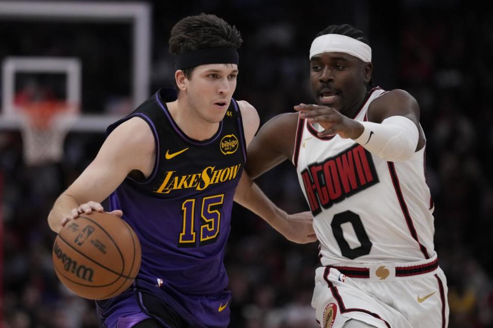 Lakers guard Austin Reaves, left, passes by Houston Rockets guard Aaron Holiday during the first half on Sunday.