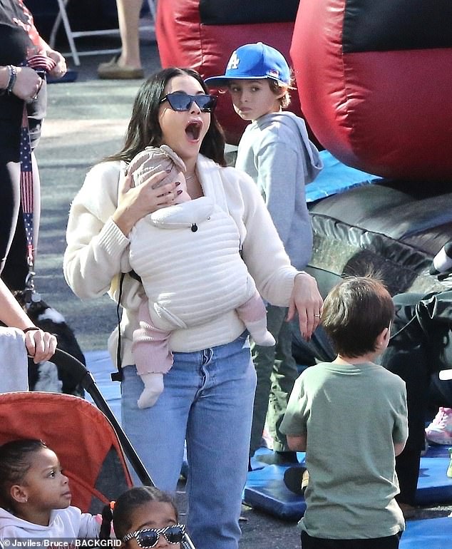 The doting mum kept Rhiannon close to her in a cream-coloured baby carrier, with her chubby little legs covered in pink trousers and her tiny feet covered in white socks.