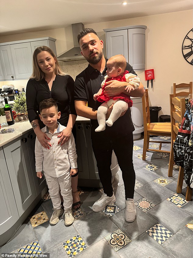 Sophia Kelemen, six months, from the Leigh area of ​​Manchester, being held by her father with her mother and older brother.