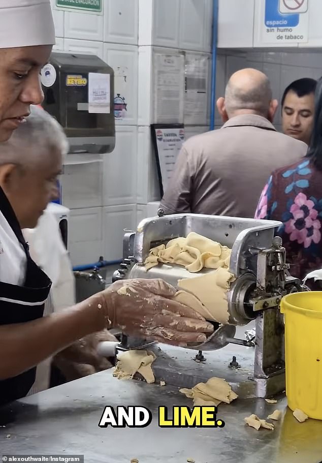 A cook prepares freshly made corn tortillas while meat is fried nearby