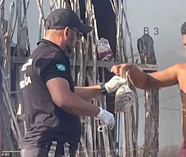 A police officer receives a bag containing the leftovers from the meal that killed four family members and hospitalized five in Parnaíba, Brazil