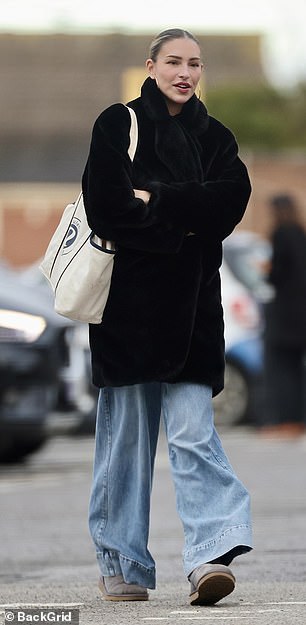 She bundled up for the cold weather in a black faux fur coat and blue jeans, paired with gray UGG boots.